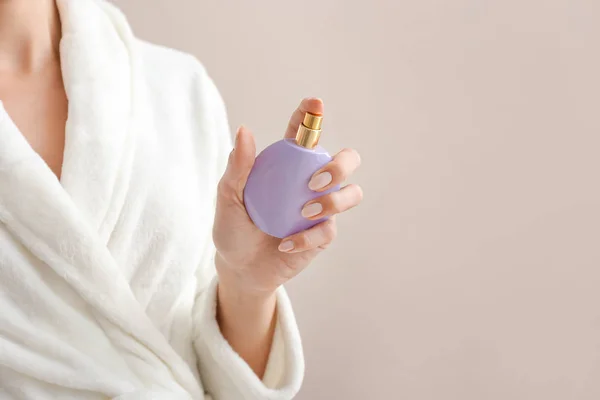 Beautiful young woman with bottle of perfume on color background — Stock Photo, Image