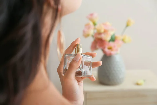 Hermosa joven con botella de perfume en casa — Foto de Stock