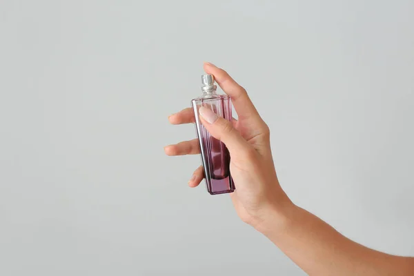 Mano femenina con frasco de perfume sobre fondo claro — Foto de Stock