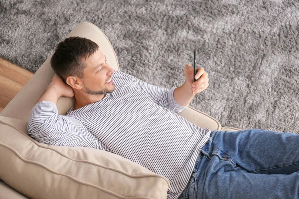 Man with mobile phone relaxing at home