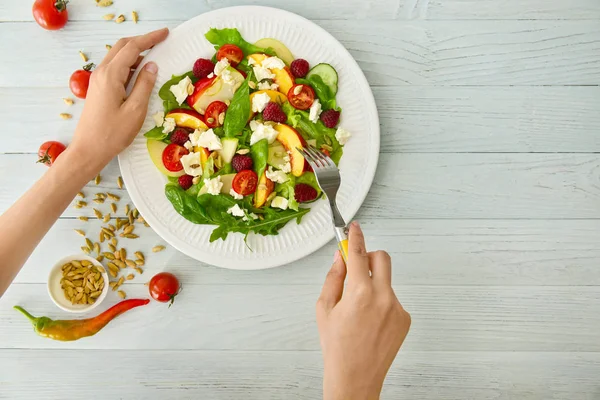 Vrouw eten smakelijke salade in de tafel, bovenaanzicht — Stockfoto