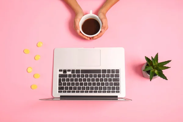 Kvinnliga händer med kopp kaffe och modern laptop på färg bakgrund — Stockfoto