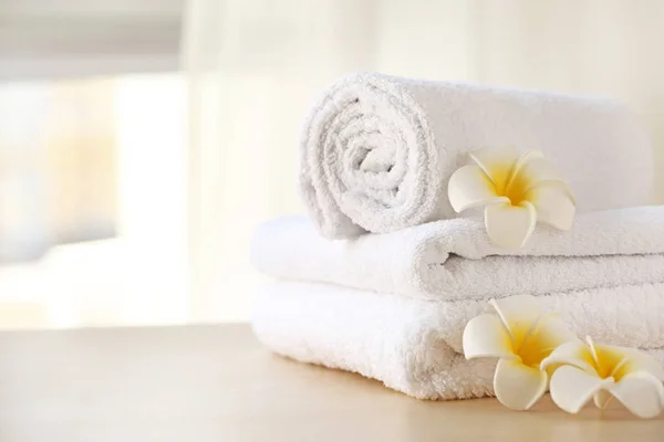 Clean towels with flowers on table in room — Stock Photo, Image