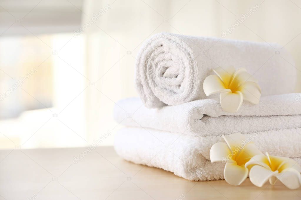 Clean towels with flowers on table in room