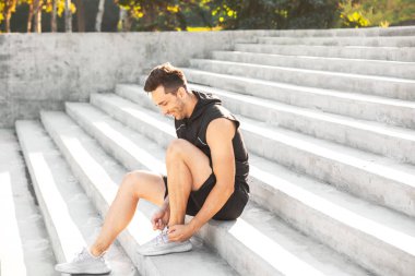 Spor ayakkabı bağcıklarını bağlayan genç bir adam.