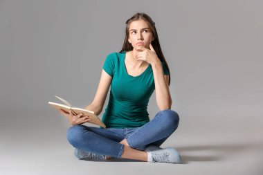Gri arka plan kitap ile Düşünceli genç kız