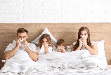 Evde yatağında grip olan bir aile.