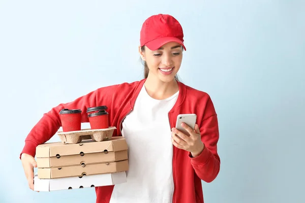 Vrouwelijke werknemer van Food delivery service met mobiele telefoon op kleur achtergrond — Stockfoto