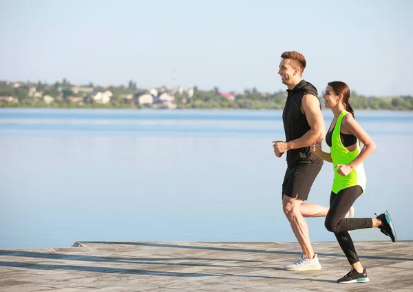 Sporty young couple running near river — Stock Photo, Image