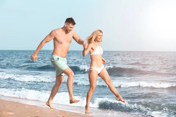 Pareja feliz corriendo en la playa — Foto de Stock