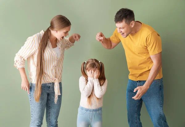 Angry parents scolding their little daughter on color background
