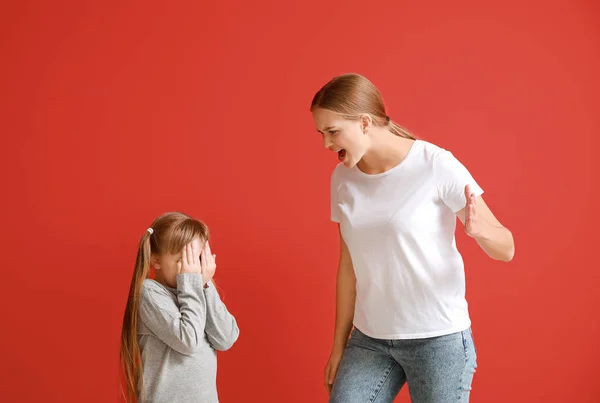 Angry mother scolding her little daughter on color background — Stock Photo, Image