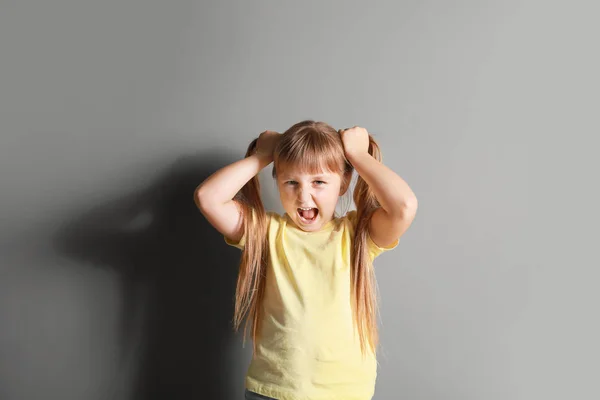 Portrait of angry little girl on grey background — Stock Photo, Image
