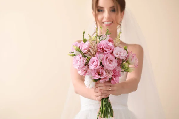 Beautiful young bride with wedding bouquet on light background — Stock Photo, Image