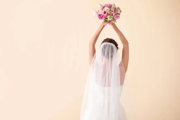 Beautiful young bride with wedding bouquet on light background, back view — Stock Photo, Image