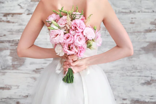 Mooie jonge bruid met bruiloft boeket op houten achtergrond, achteraanzicht — Stockfoto