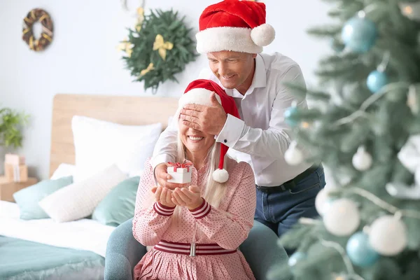 Mature husband giving his wife Christmas present at home — Stock Photo, Image