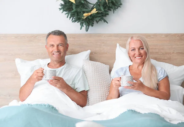 Happy äldre par dricker varm choklad i sängen hemma på julafton — Stockfoto
