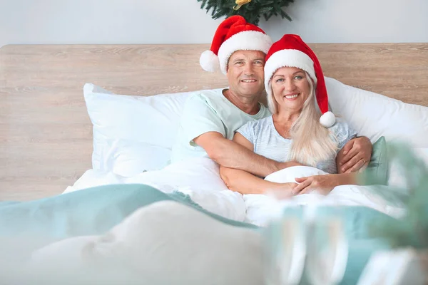 Happy mature couple sitting in bed at home on Christmas eve — Stock Photo, Image