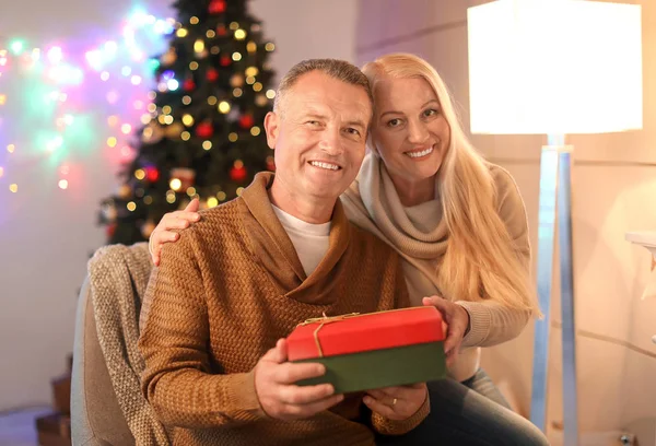 Happy äldre par med julklapp hemma — Stockfoto