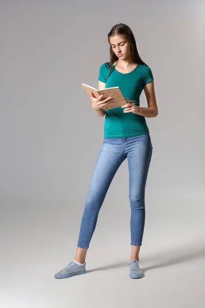 Young girl with book on grey background — Stock Photo, Image