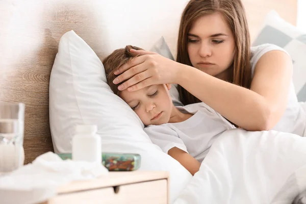 Mamma tar hand om sin lille son sjuk med influensa hemma — Stockfoto