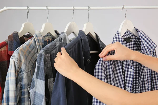 Frau wählt Kleidungsstücke, die am Regal hängen — Stockfoto