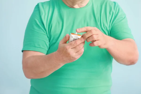 Diabetic man with digital glucometer on light background, closeup — Stock Photo, Image