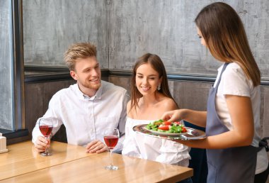Garson restoranda genç çift için salata getiren