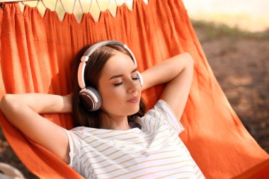 Açık havada hamakta dinlenmiş kulaklıklı güzel genç kadın
