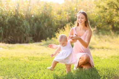 Anne küçük bebeğine dışarıda yürümeyi öğretiyor.