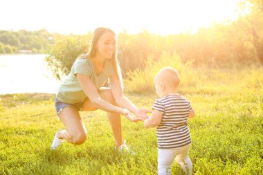 Anne küçük bebeğine dışarıda yürümeyi öğretiyor.
