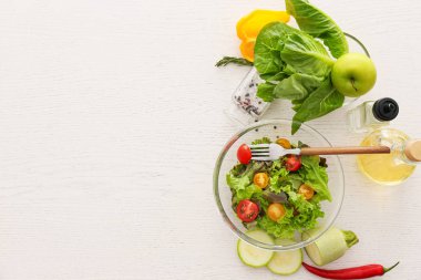 Beyaz masada lezzetli sebze salatası ve malzemelerle Kase