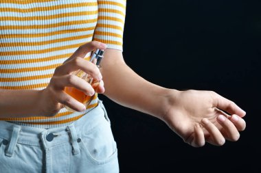 Koyu arka planda parfüm şişesi ile genç kadın, closeup