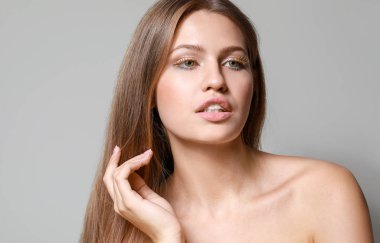 Gri arka planda yaratıcı kirpikleri olan genç kadın