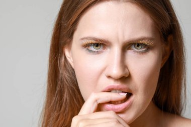 Gri arka planda yaratıcı kirpikleri olan genç kadın