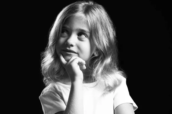 Black and white portrait of thoughtful little girl on dark background