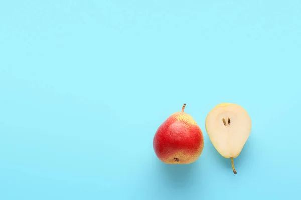 Whole and cut ripe pears on color background