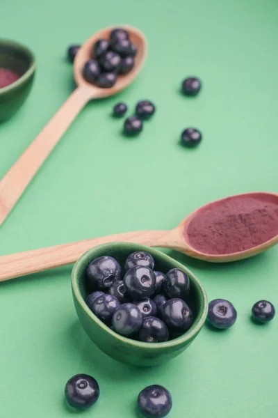 Fresh acai berries with powder on color background — Stock Photo, Image