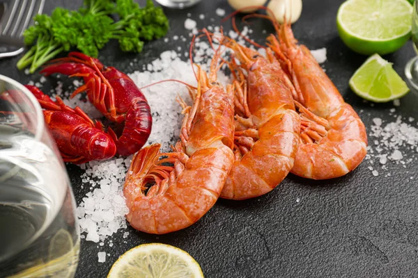 Tasty shrimps with crayfish, glass of water and salt on dark background — Stock Photo, Image