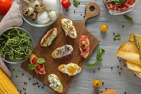 Tablero con diferentes sándwiches sabrosos en mesa de madera — Foto de Stock