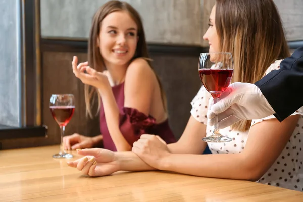 Ober brengt wijn voor jonge vrouwen in Restaurant, close-up — Stockfoto