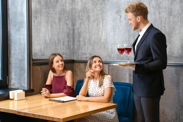 Servitör föra vin för unga kvinnor i restaurang — Stockfoto