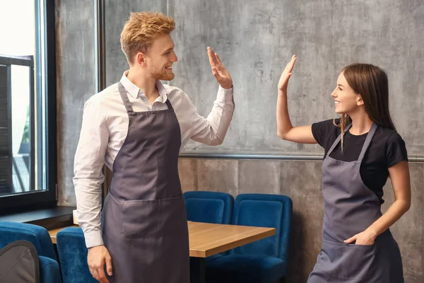 Unga servitörer ger high-five till varandra i restaurang — Stockfoto