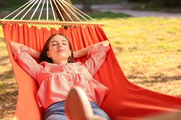 Beautiful young woman resting in hammock outdoors — Stock Photo, Image