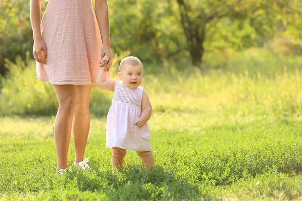 Mother teaching her little baby to walk outdoors — Stock Photo, Image