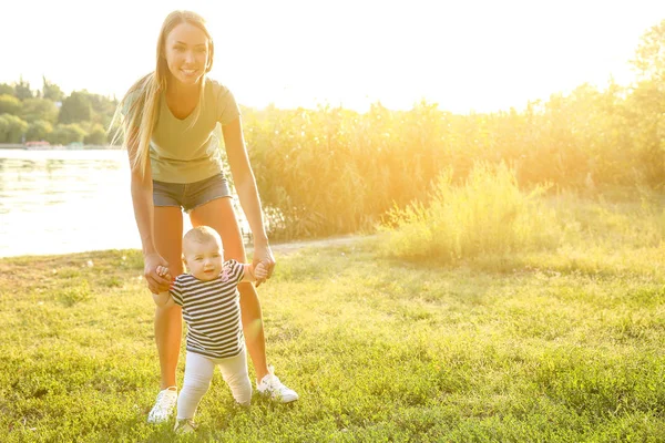 Mãe ensinando seu bebê a andar ao ar livre — Fotografia de Stock