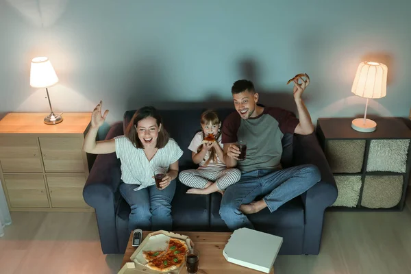 Happy family eating pizza while watching TV at home — Stock Photo, Image