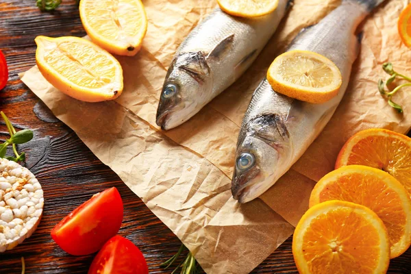 Fresh sea bass with ingredients on wooden table — Stock Photo, Image