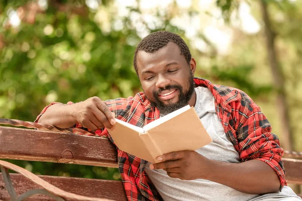 African-American man reading book in park — Stock Photo, Image